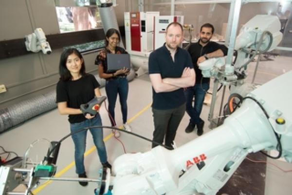 Faculty and three students behind robotic tools