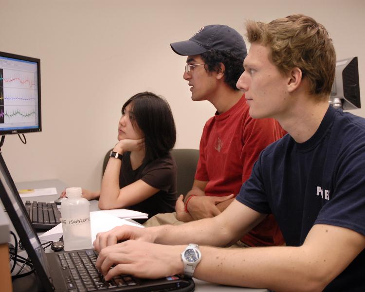 Three students working at two computers