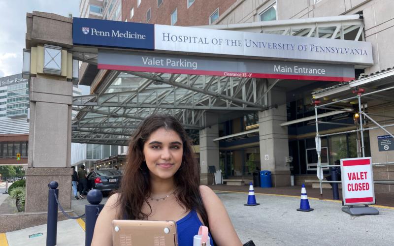 Aarushi Parikh standing in front of the entrance of the Hospital of the University of Pennsylvania
